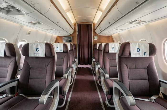 Vue intérieure grand angle d'un couloir d'avion commercial révélant la configuration de sièges sans rangée B