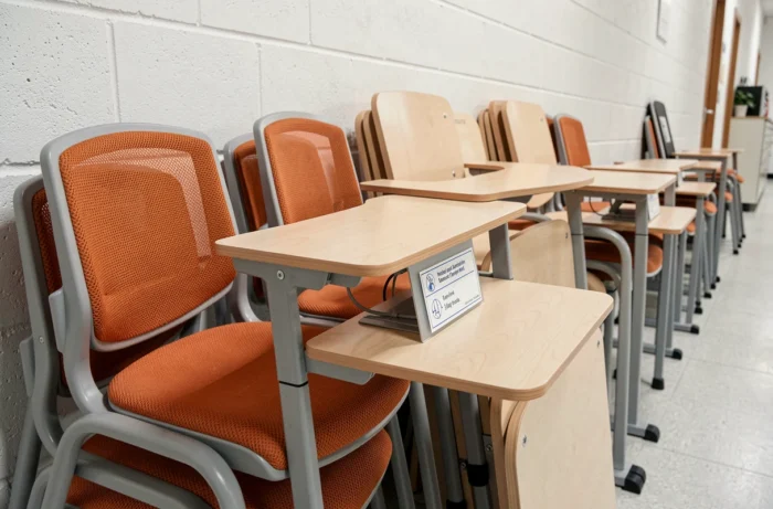 Détail de chaises et bureaux scolaires ergonomiques empilés dans un couloir d'école, illustrant la qualité du mobilier scolaire