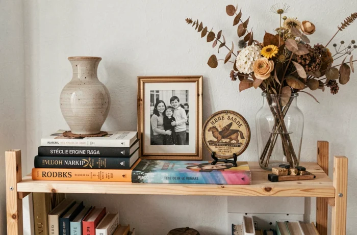 Étagère avec des objets personnels disposés naturellement : céramique artisanale, livres de poche, photo encadrée en noir et blanc et souvenir de voyage