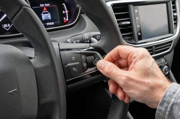Main appuyant sur le bouton de réinitialisation de la pression des pneus sur le tableau de bord d'une Peugeot 2008
