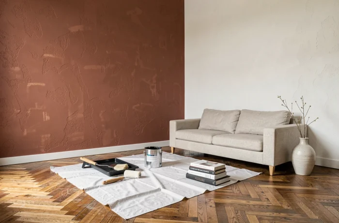 Séjour en cours de rénovation avec mur accent en terracotta et outils de peinture au sol
